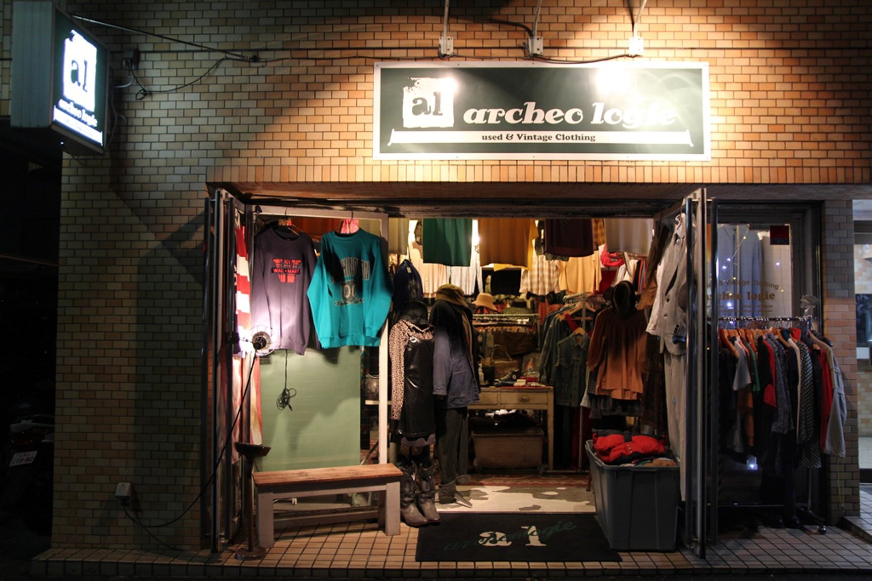 服が並んでいる古着屋「archeologie」の夜の外観