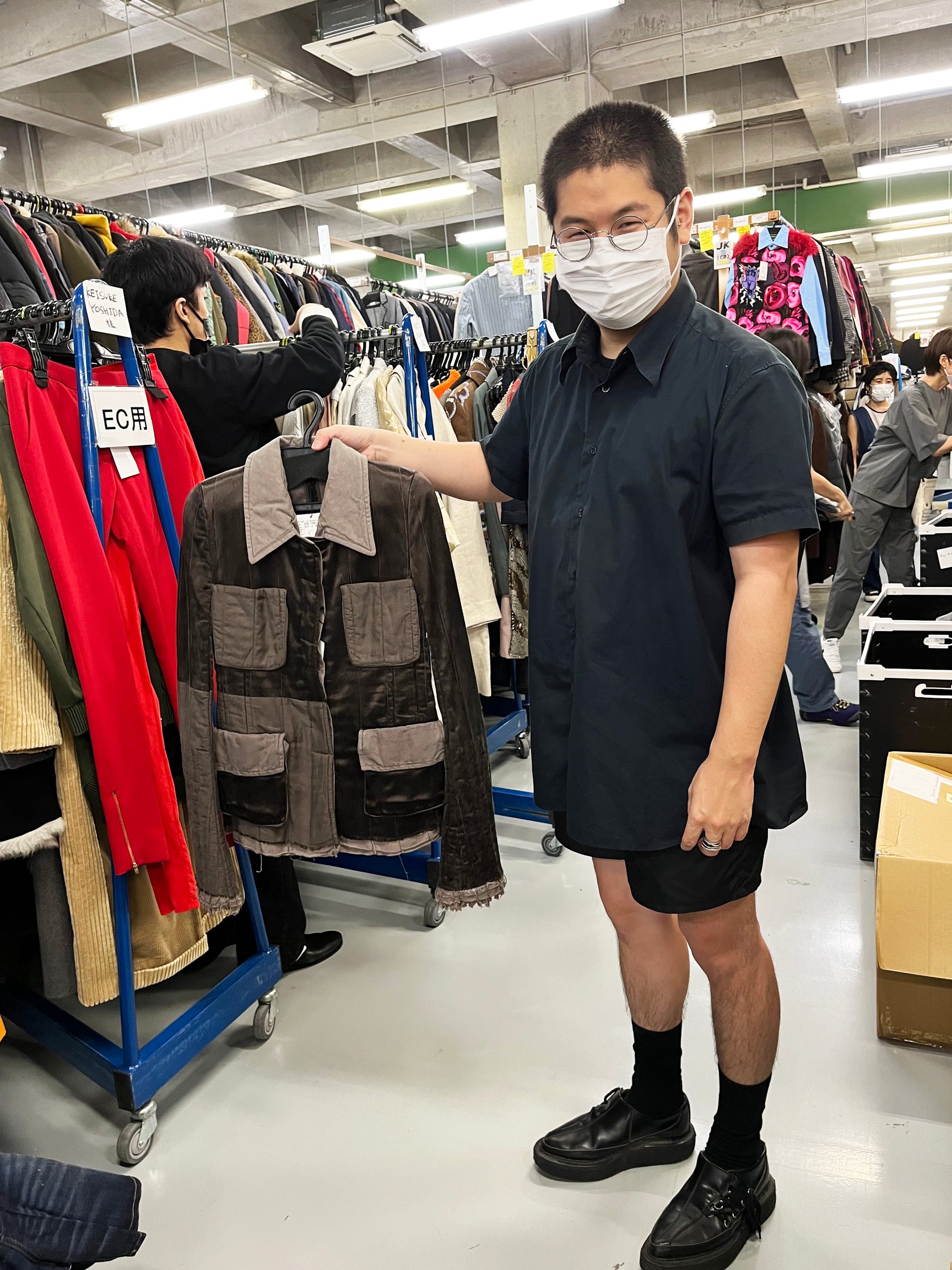 ブラウンのアウターを手に持った男性