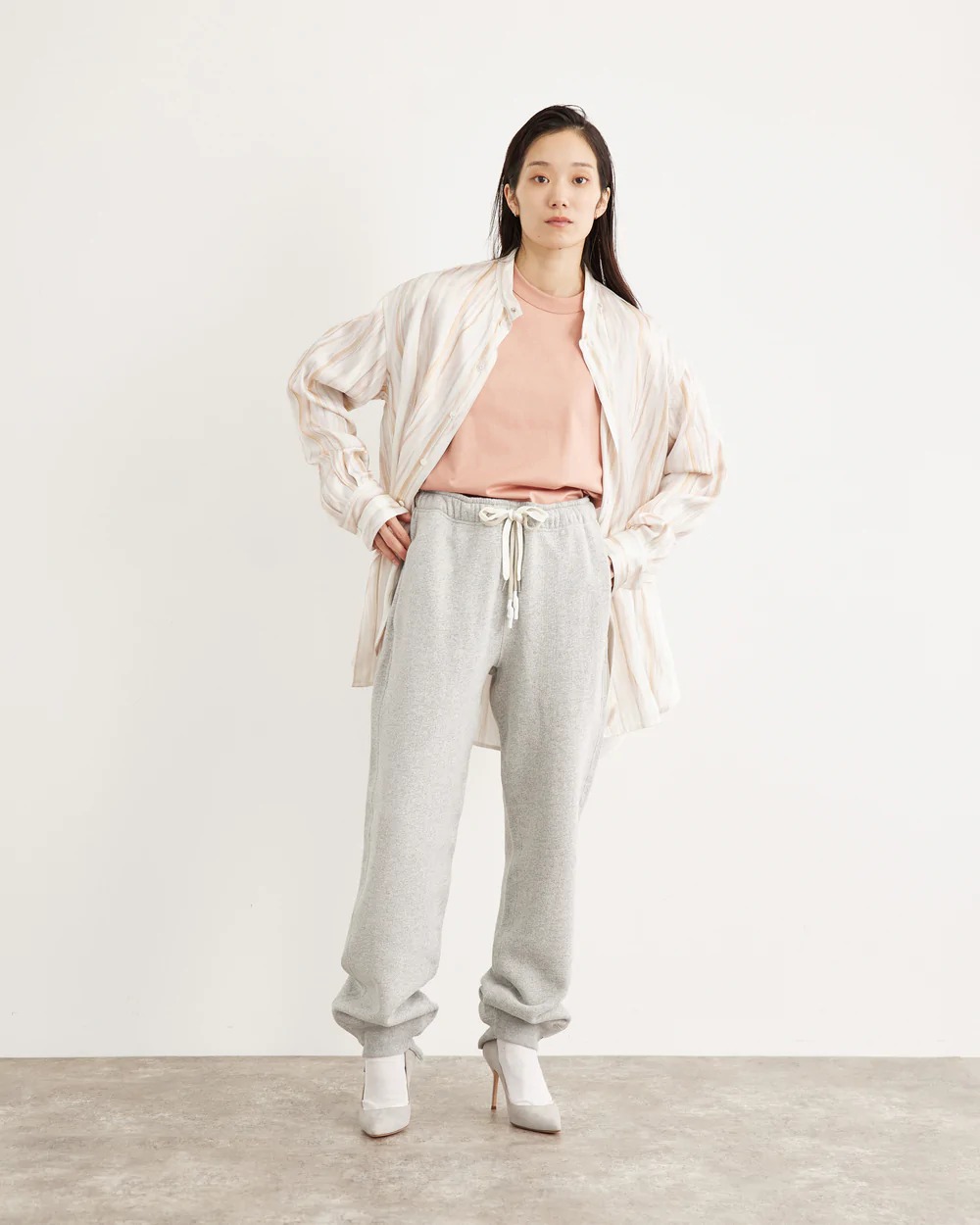 ピンクのTシャツにシャツを羽織った女性モデル