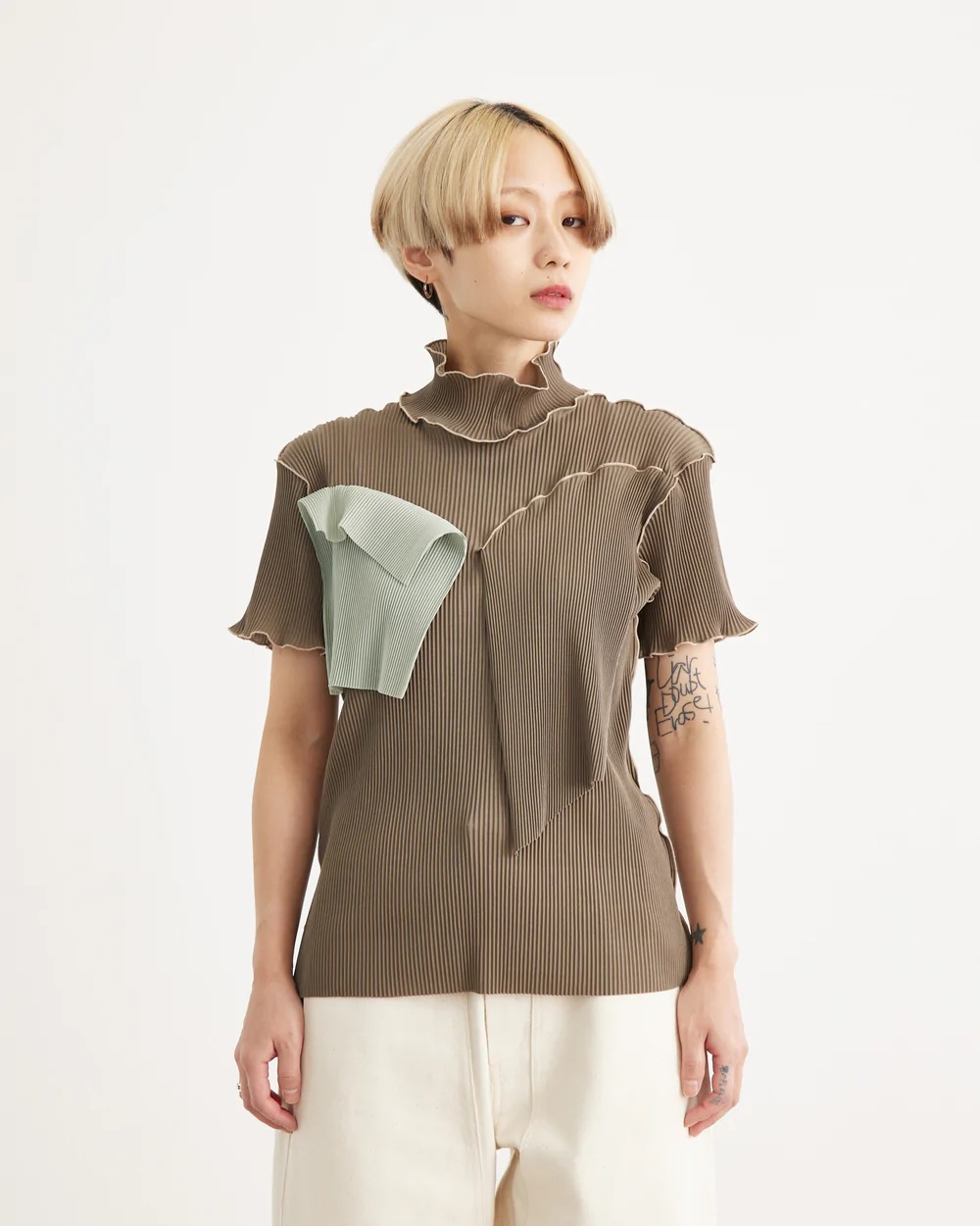 グレーのプリーツトップスを着用した女性モデル