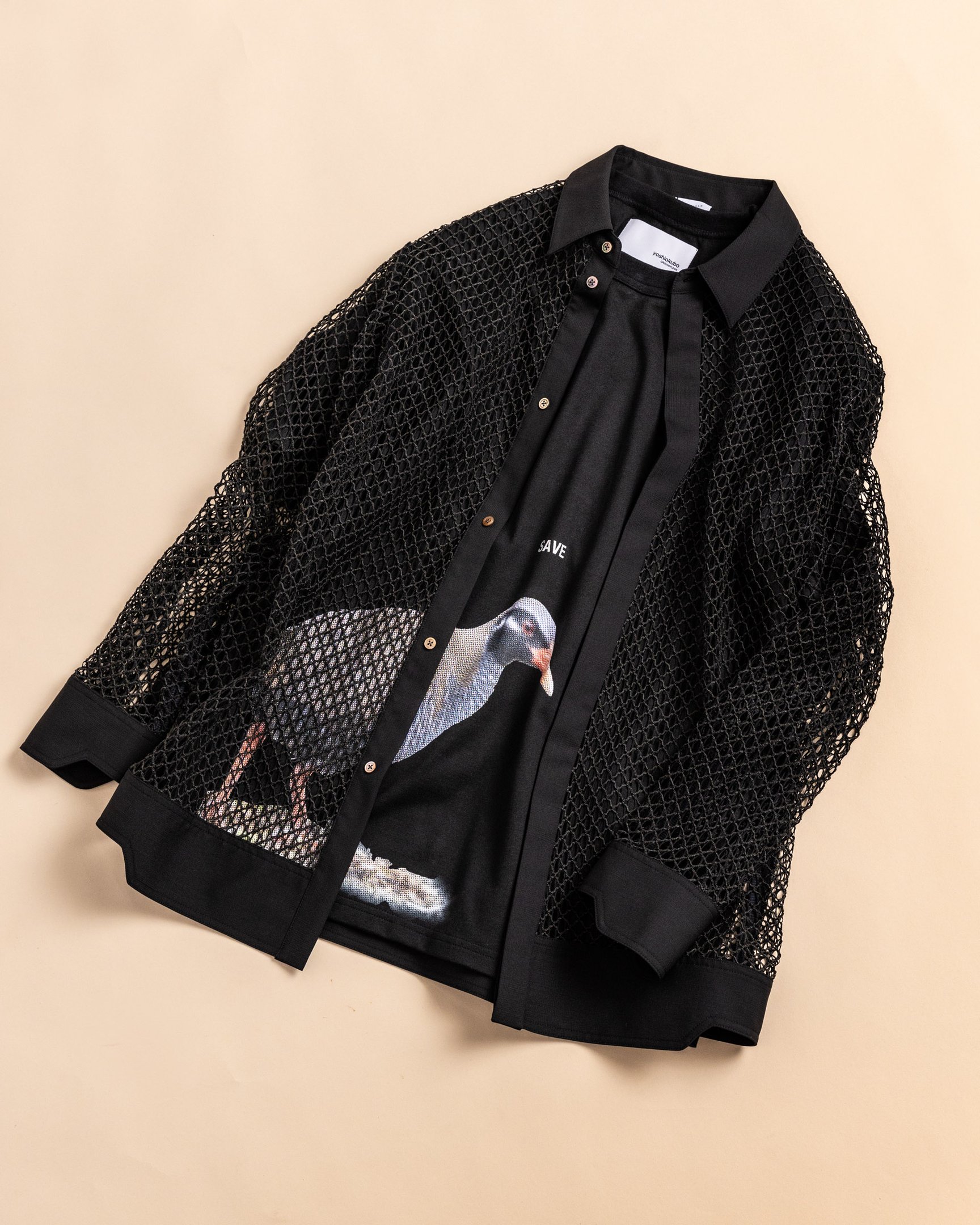 黒いプリントTシャツに黒のレースTを合わせてるルック