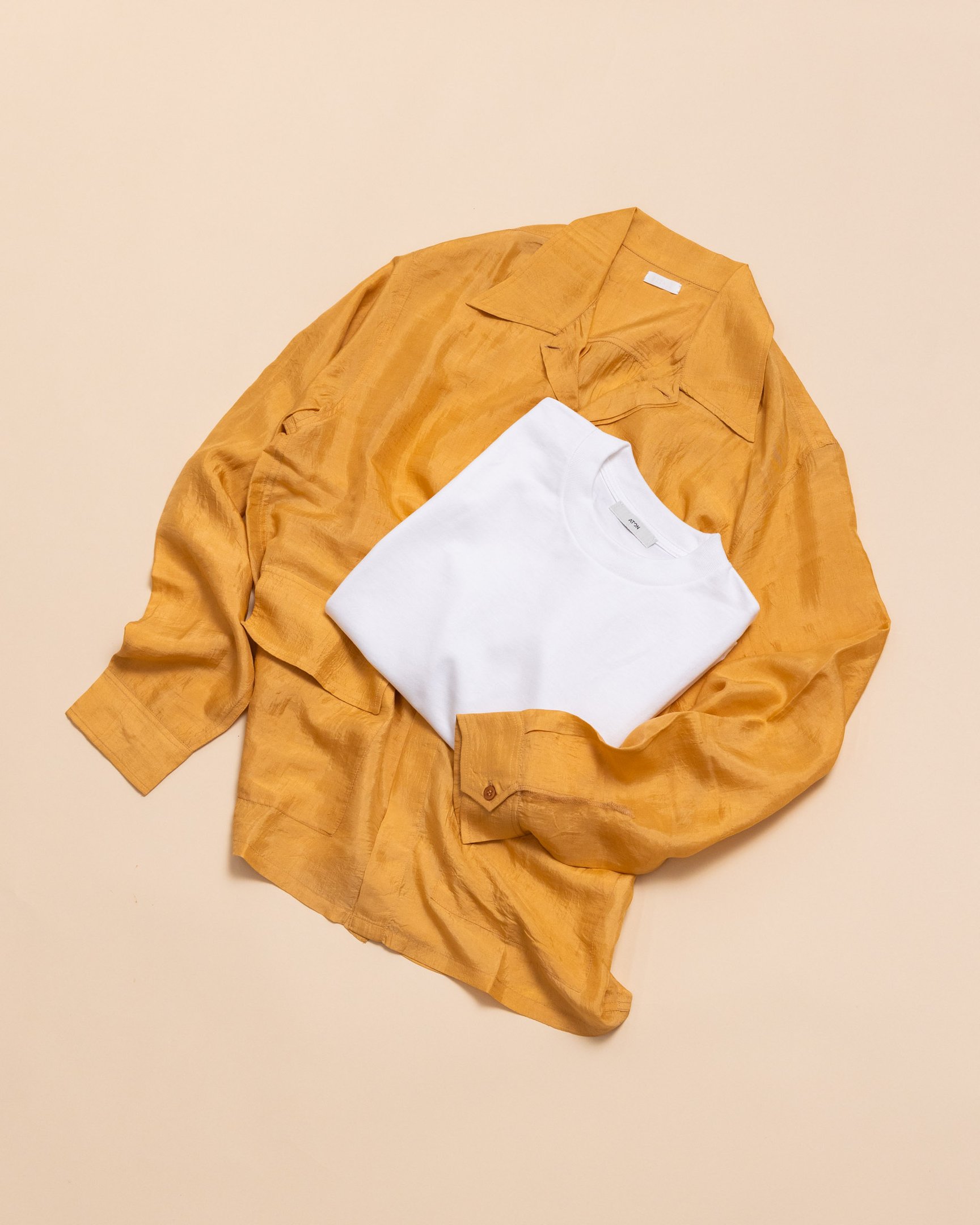 オレンジのシャツの上に畳まれた白T