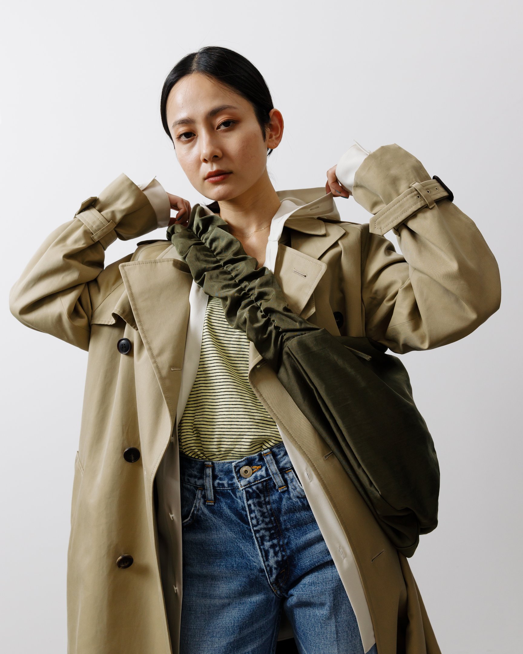 トレンチコートにショルダーバッグを合わせた女性モデル