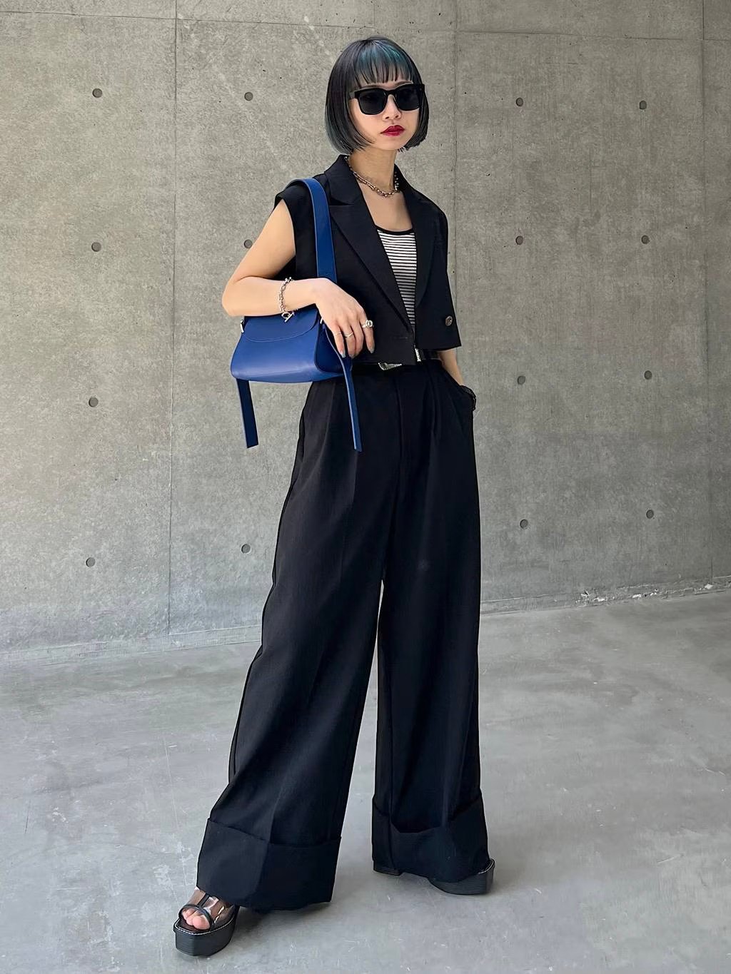 ブラックのベストとパンツのセットアップを着用した女性