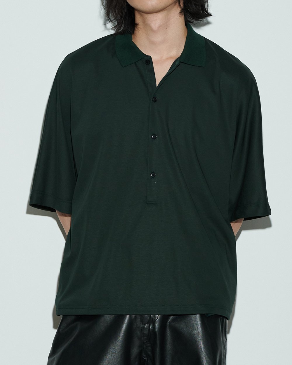 グリーンのオーバーサイズポロシャツを着用した男性モデル