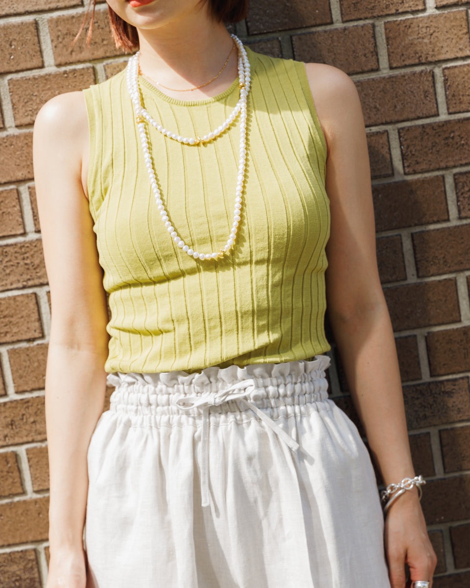 女性のスナップ画像。リネンシルクのハーフパンツにパールのネックレスのスタイリング。