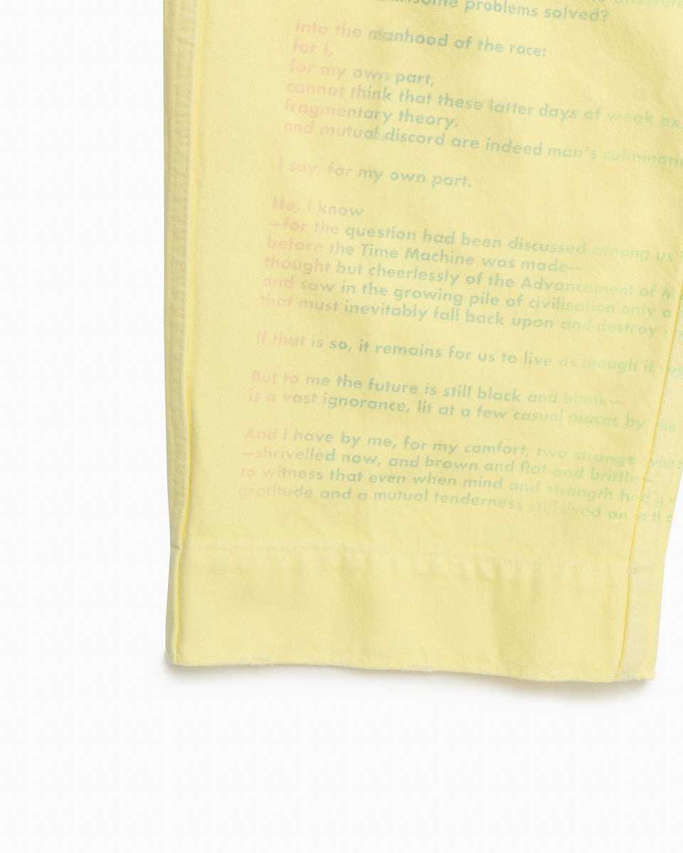 英字のプリントが施されたイエローのパンツの右裾