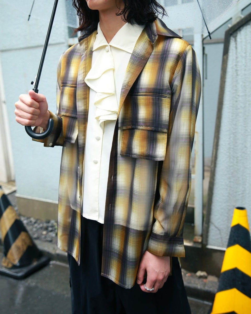 ミオズモーキーのチェックシャツを羽織った男性