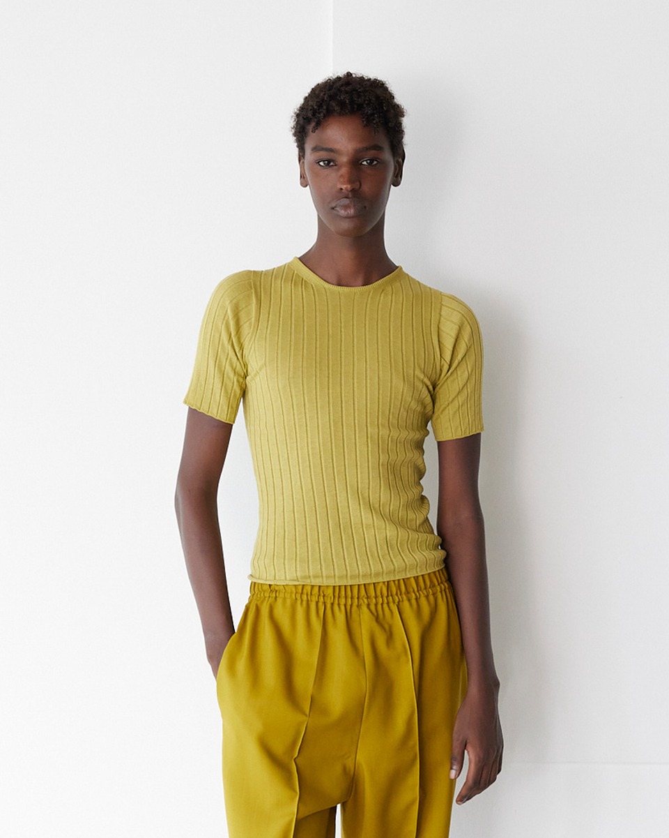 女性のルック画像。深いイエローカラーのパンツとのスタイリング。