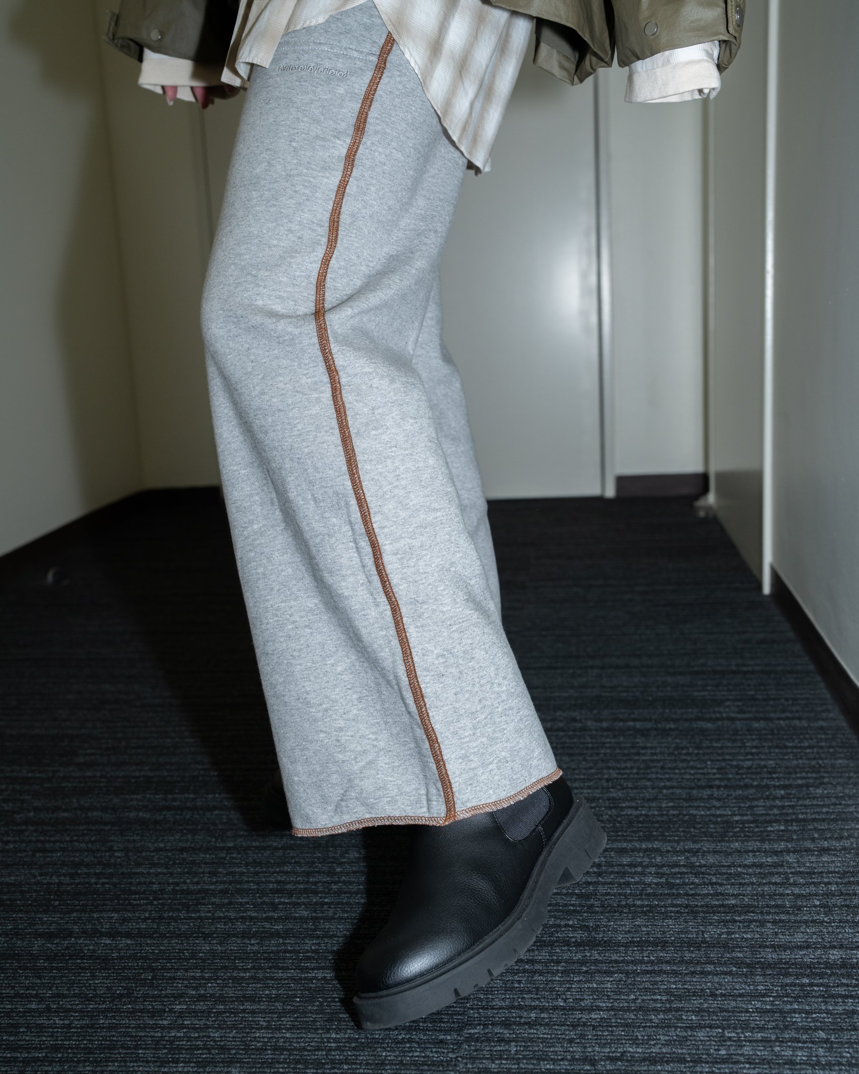 カーキのブルゾンとスェットパンツのスタイリングをした女性。