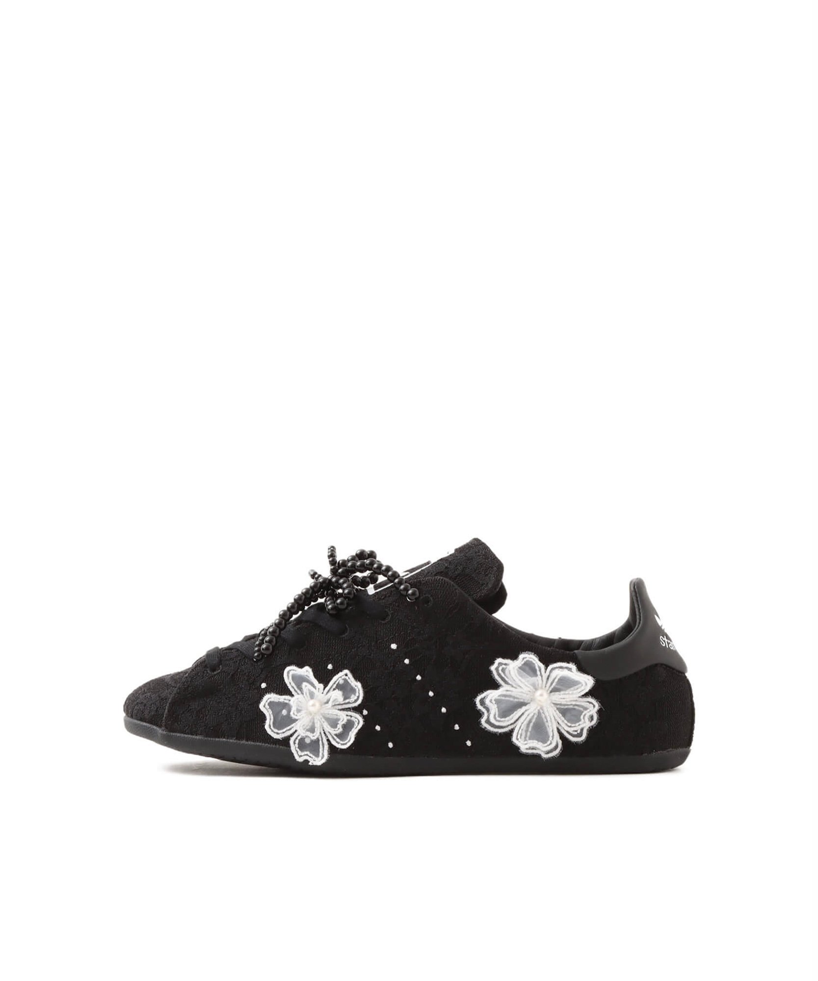 白い花のモチーフをあしらった黒いスニーカー