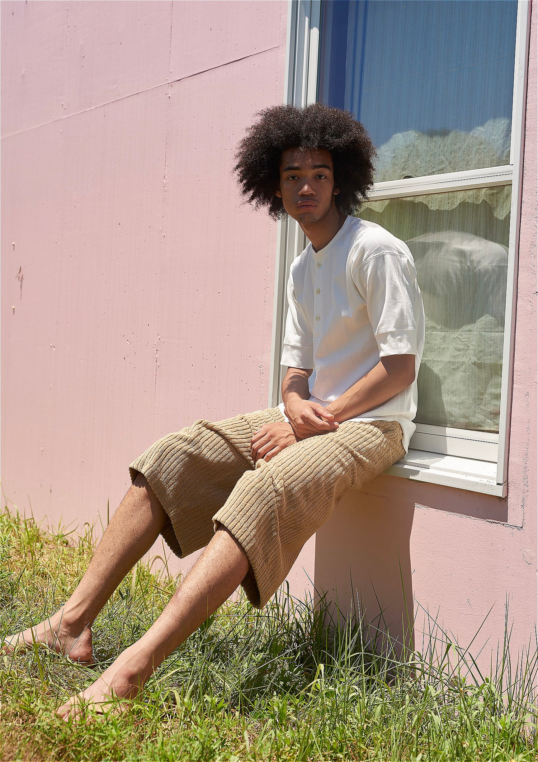 アンスクリアのベージュのパイルショーツと白Tを着た男性モデル