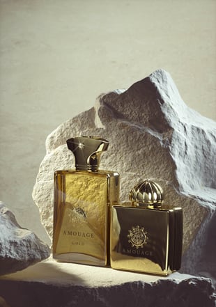 石の手前に置かれたゴールドカラーのサイズ違いの香水ボトル2つ