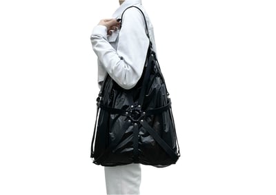 肩にかかっている黒いハーネスバッグ