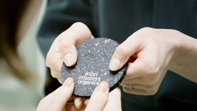 アップサイクルで作られたコースターを手渡ししている写真