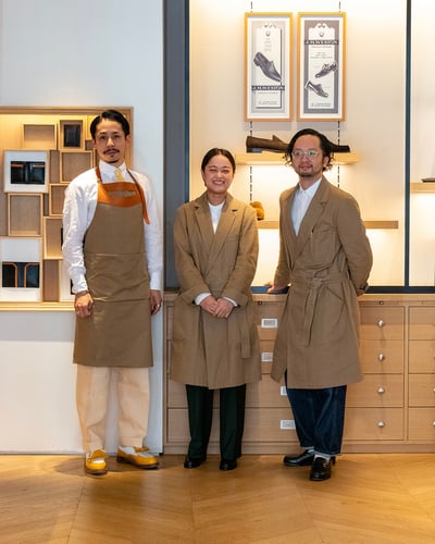 茶色のエプロンとコートをつけた女性1人と男性の2人