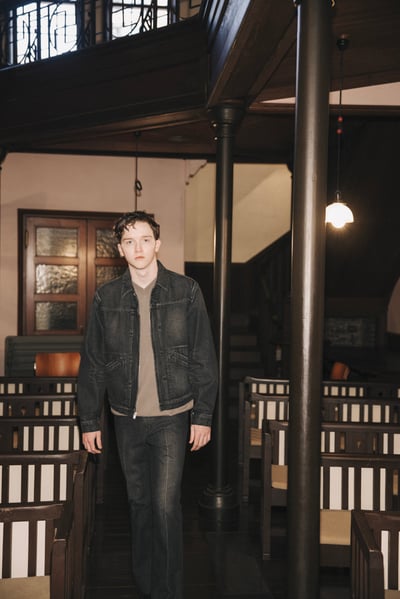 ウィーウィルがラングラーとコラボレーションした黒いデニムジャケットを着用したモデル