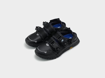 ヒールストラップや青いインソールに「ジュンヤ ワタナベ マン」のロゴを配した東京デザインスタジオ ニューバランスの黒いサンダル