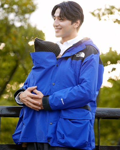 ザ・ノース・フェイスの青いマタニティ用ジャケットを着用した男性