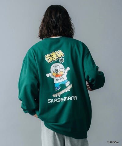 うまい棒のキャラクターをあしらったグリーンのスウェットを着用した男性