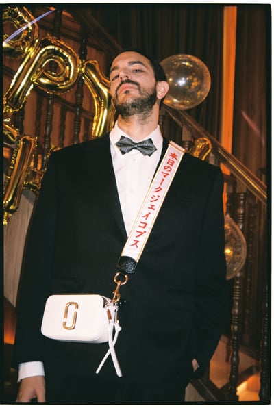 タキシードと白いショルダーバッグを着用した男性