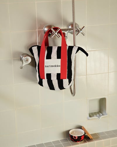 壁にかけられた黒と白のストライプに赤い取っ手を付属したトートバッグ