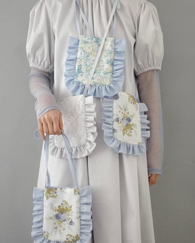 白いワンピースを着用しフリル付きのショルダーバッグを持った女性