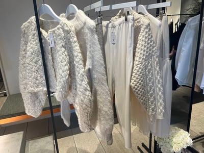 ラックにかけられた白いニットカーディガンやスカート