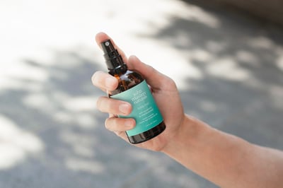 緑のラベルが貼られたスプレーを手に持っている様子