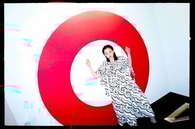 赤い円の前でポーズをとるのん