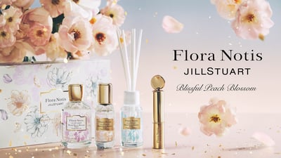 ピーチブロッサムが舞う背景にコレクションアイテムのフレグランスなどが整列している