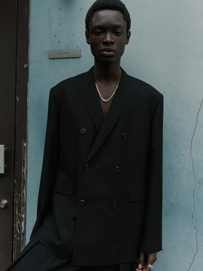 青色の壁の前に立つモデル