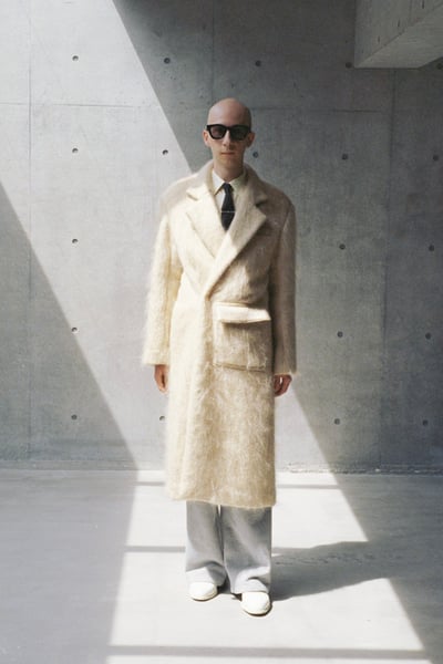 白いロングコートを着用した男性モデル