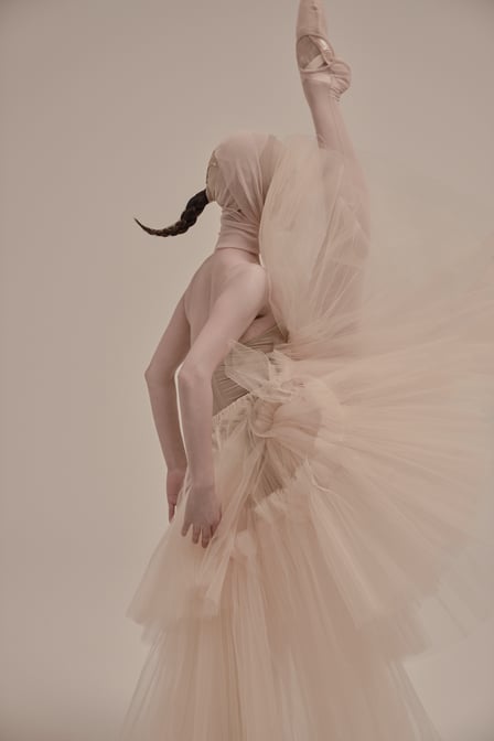ベージュの衣装を纏ってポーズをとる女性バレエダンサー