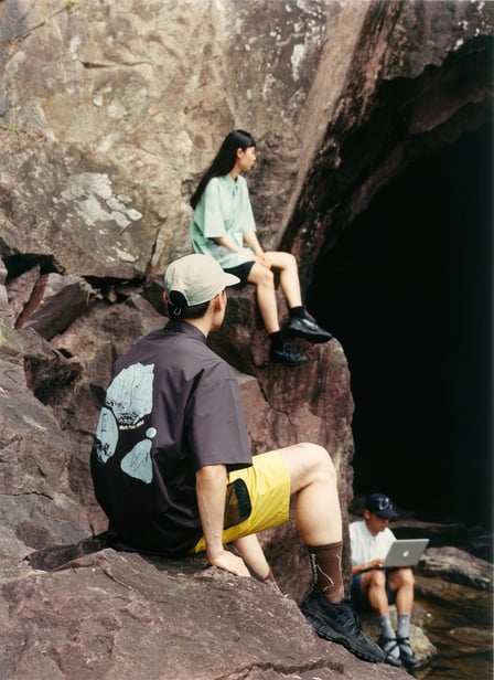 岩場に座る男女3人