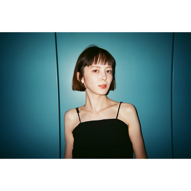 青い背景にボブスタイルの女性が映る写真