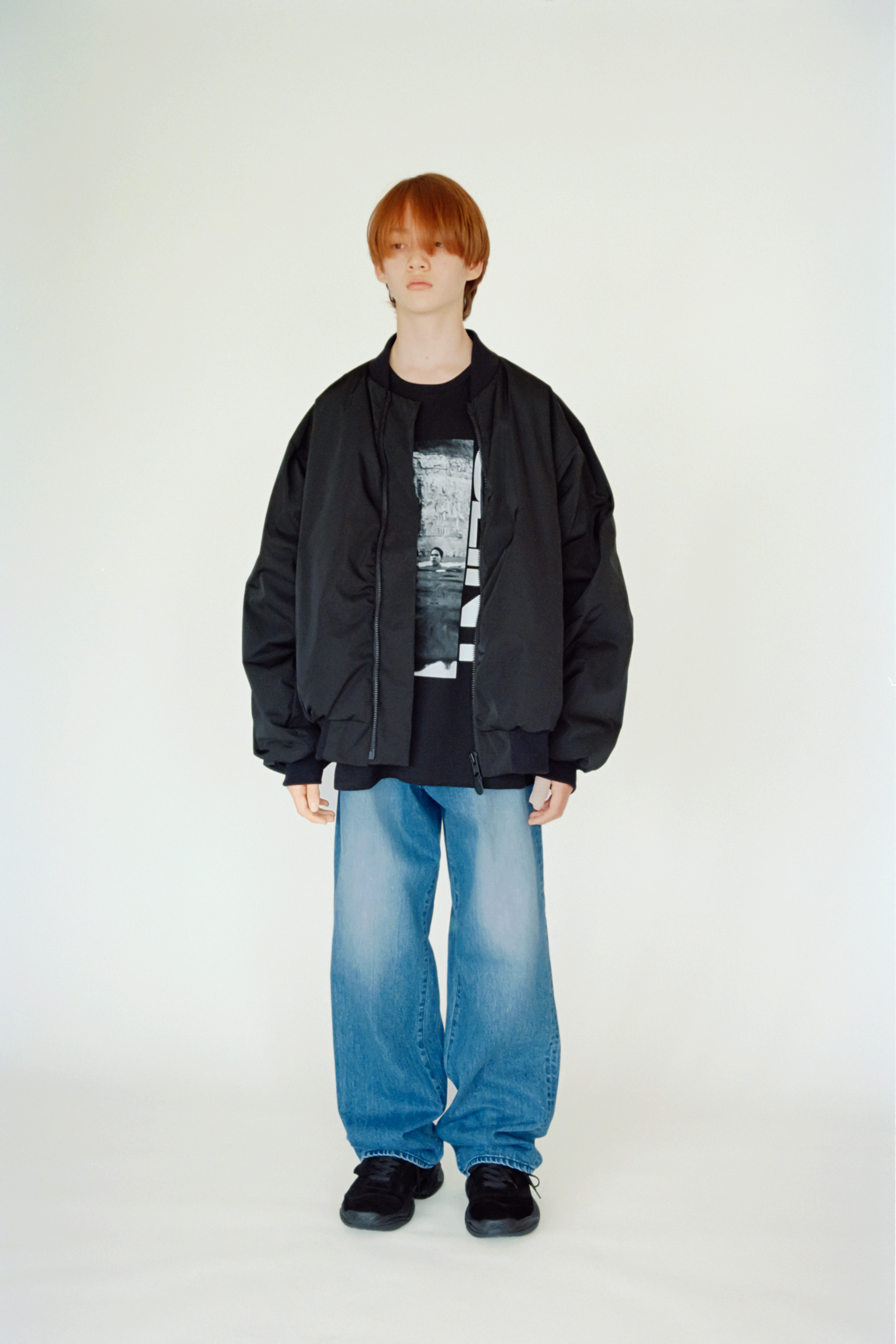Oversized black bomber over a black graphic T-shirt with light blue wide-leg jeans and black sneakers